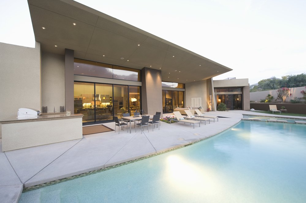 Swimming pool and paved seating area in front of modern home